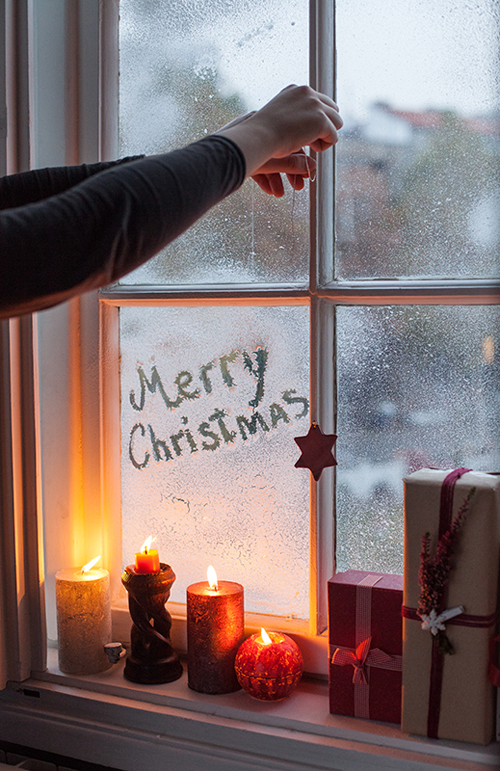 Lighting christmas candles next to the window